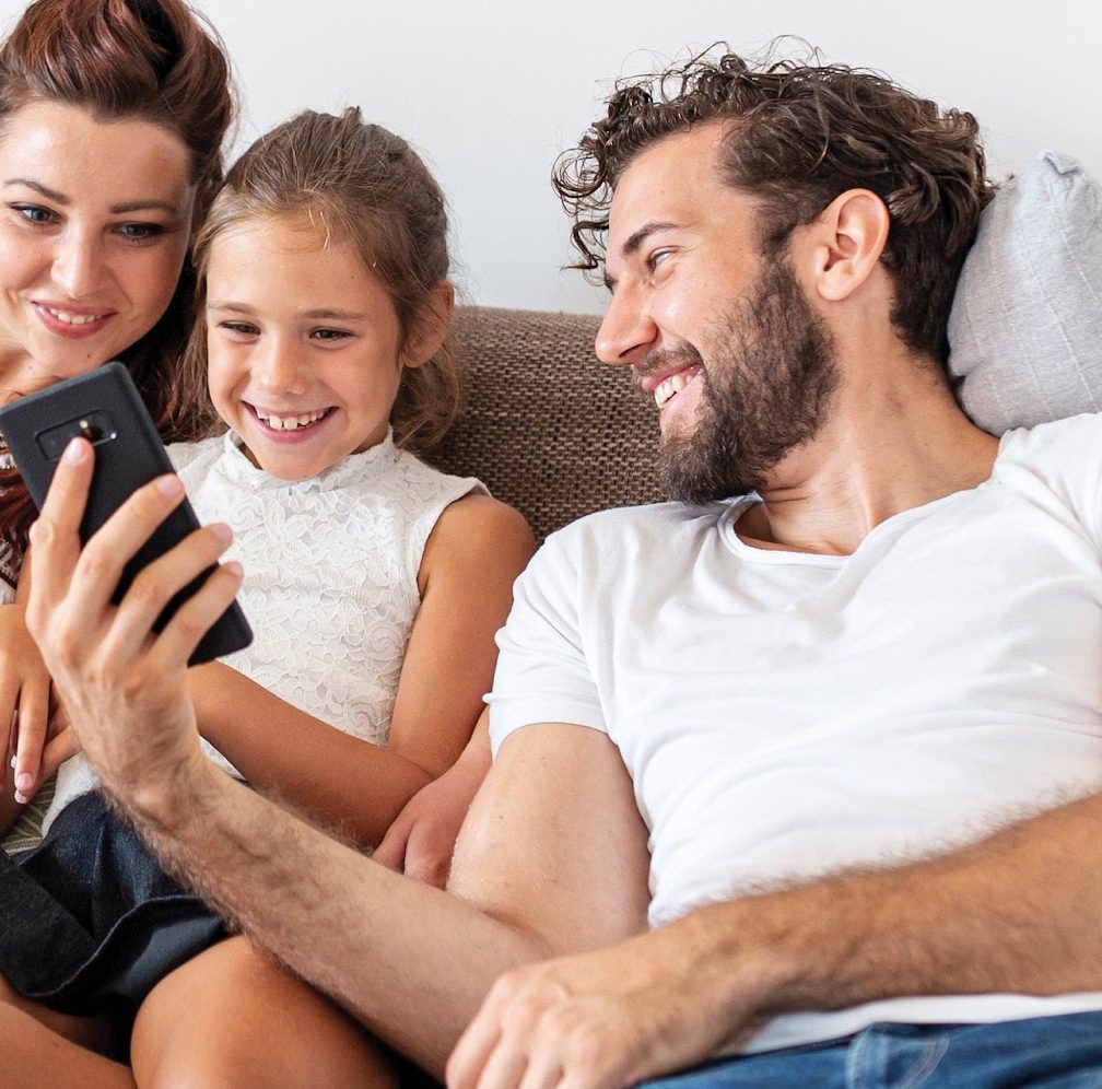 Familia mirando el celular en el sillón